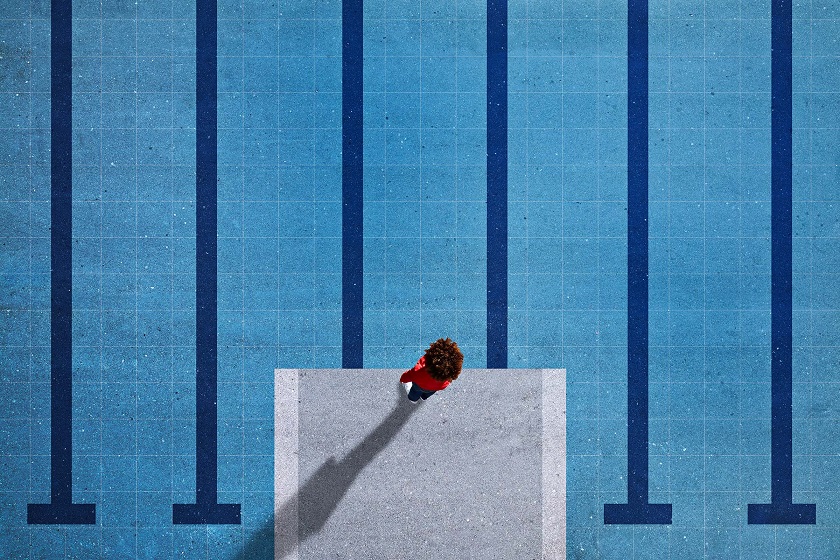 Ein Mensch blickt von einem Sprungturm auf ein Schwimmbecken