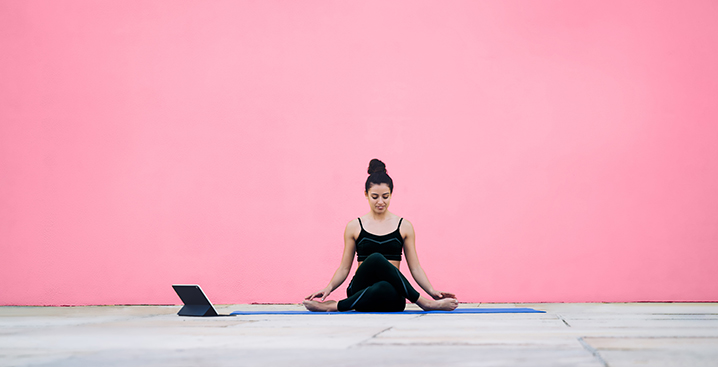 Woman doing yoga on a pink background