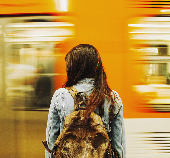 Mujer parada de espaldas frente a un tren en movimiento en el metro de la Ciudad de México.