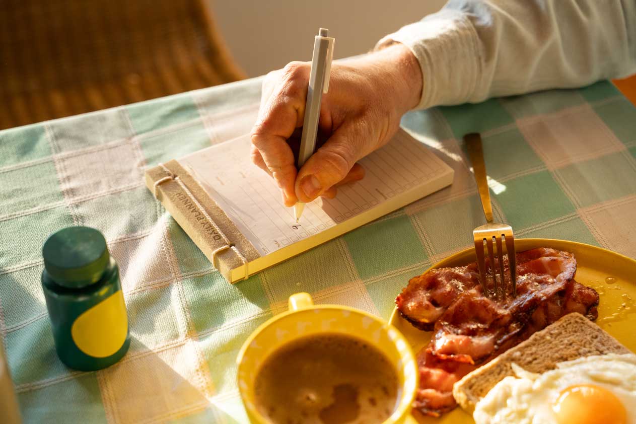 A breakfast plate with a hand taking notes
