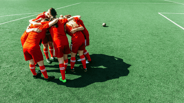Soccer players huddle on a field before a match, symbolizing national teams, global competition, and opportunities across countries worldwide.