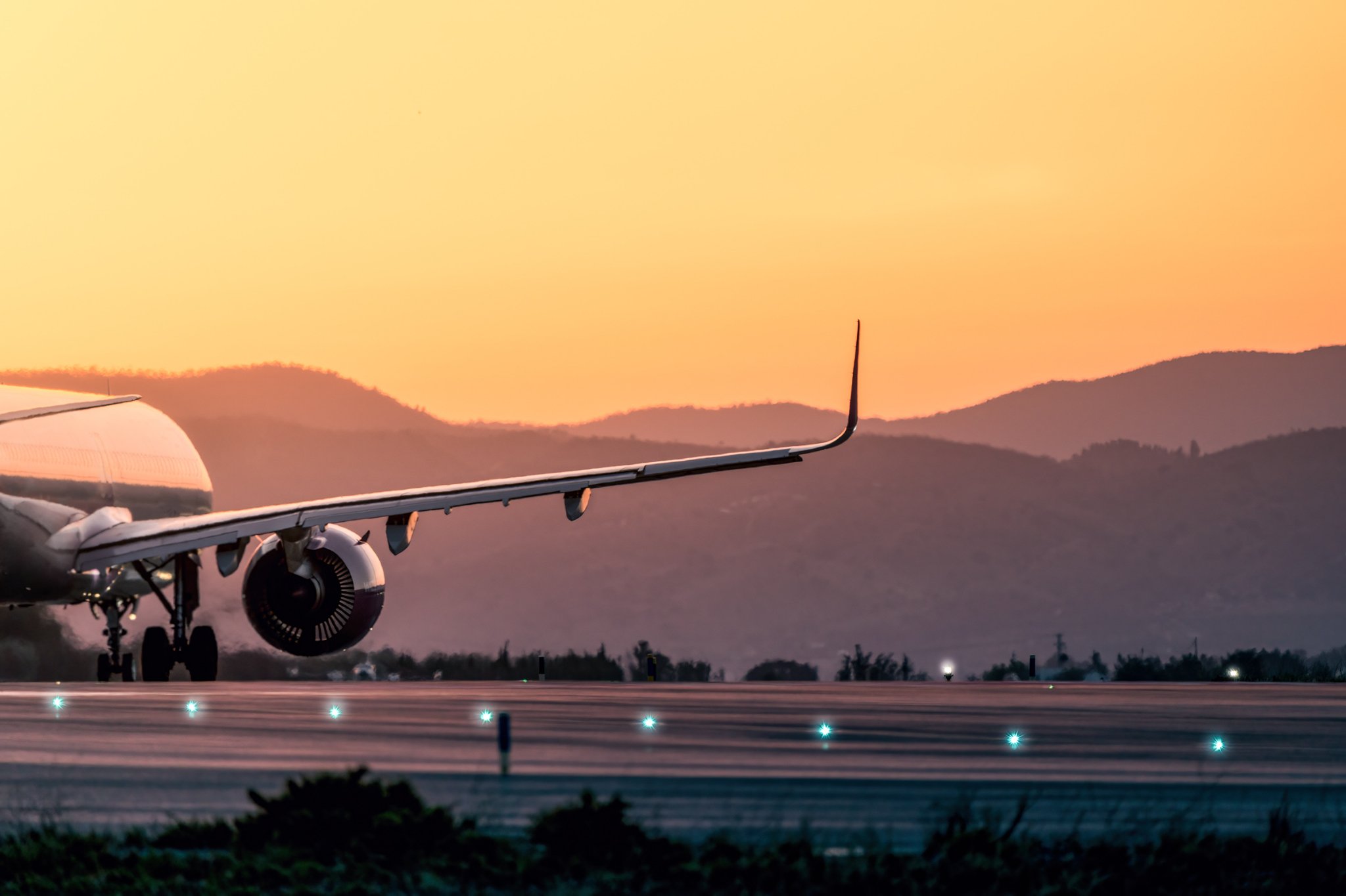 Airplane on a runway at sunset with distant mountains in the background