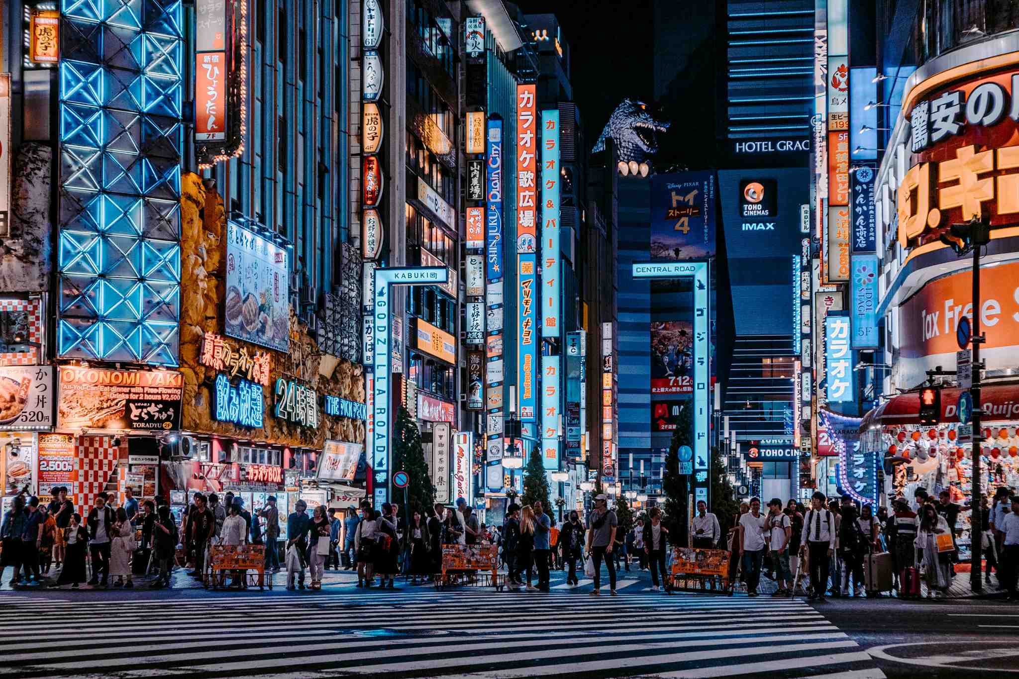 Nighttime city street with illuminated signs and pedestrians at a busy intersection