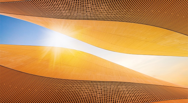 Curvas arquitectónicas doradas abstractas, con la luz del sol atravesando una abertura central.