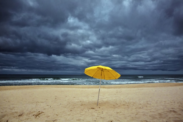 yellow umbrella on a beach under gloomy sky