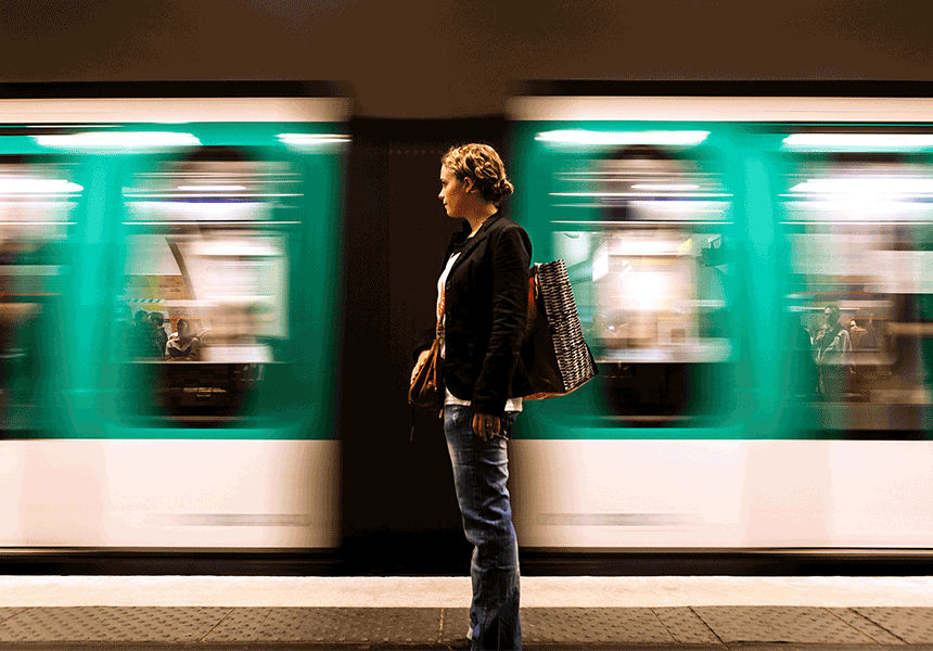 Woman standing on a train platform while train is speeding by