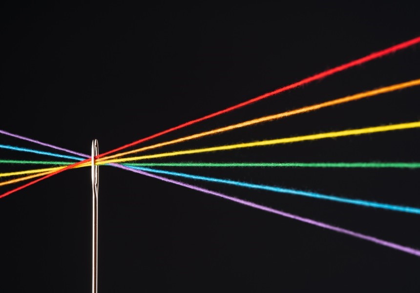 彩虹顏色的線穿過針孔，象徵多元化收益來源