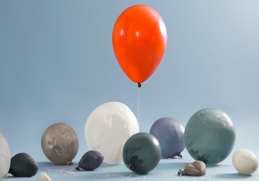 Image of a red inflated balloon and multiple grey deflated balloons