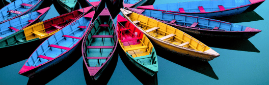 High view of olourful boats arranged next to one another on blue water.