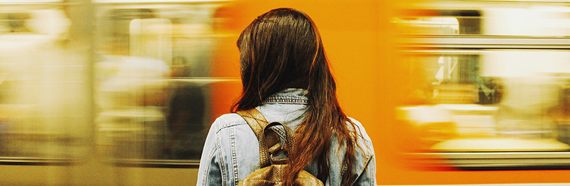 Girl waiting on the train station platform as a train rushes past