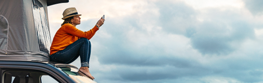 Woman sitting on her car using her mobile phone