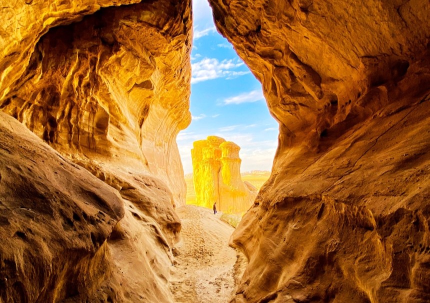 Natural rock canyon passage with warm, golden tones and an opening toward the sky