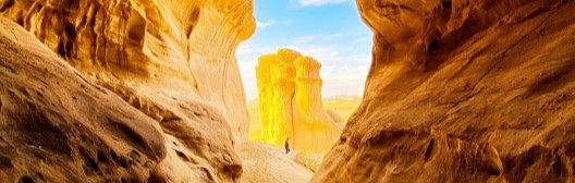 Natural rock canyon passage with warm, golden tones and an opening toward the sky