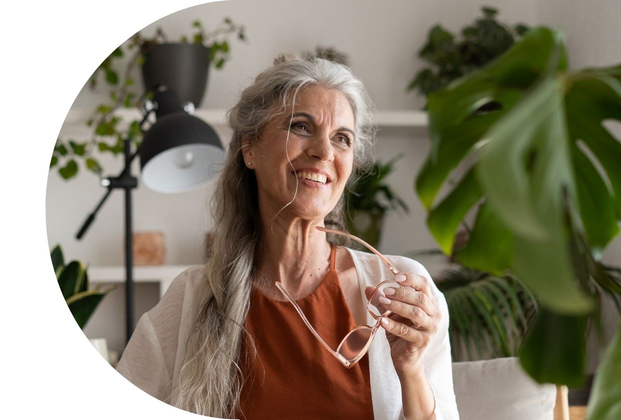 older lady smiling holding her eyeglasses