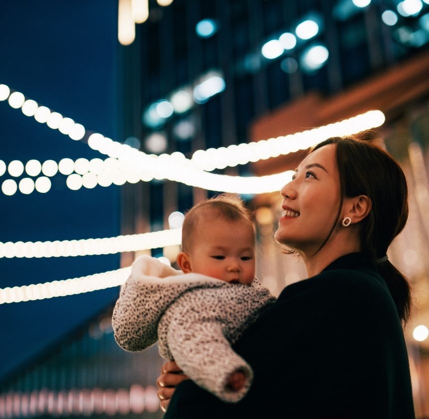 woman holding baby looking at lights