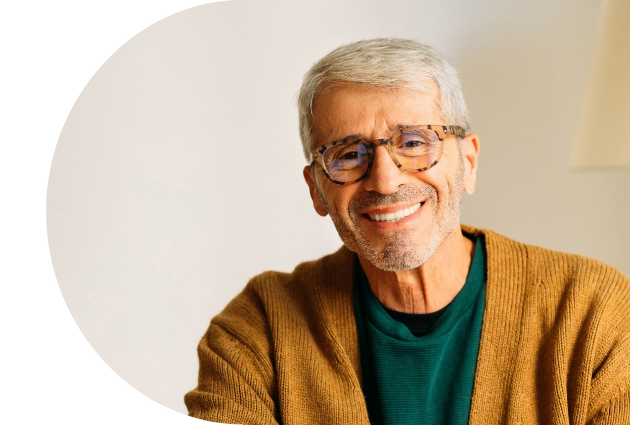 old man in glasses and cardigan, smiling at camera