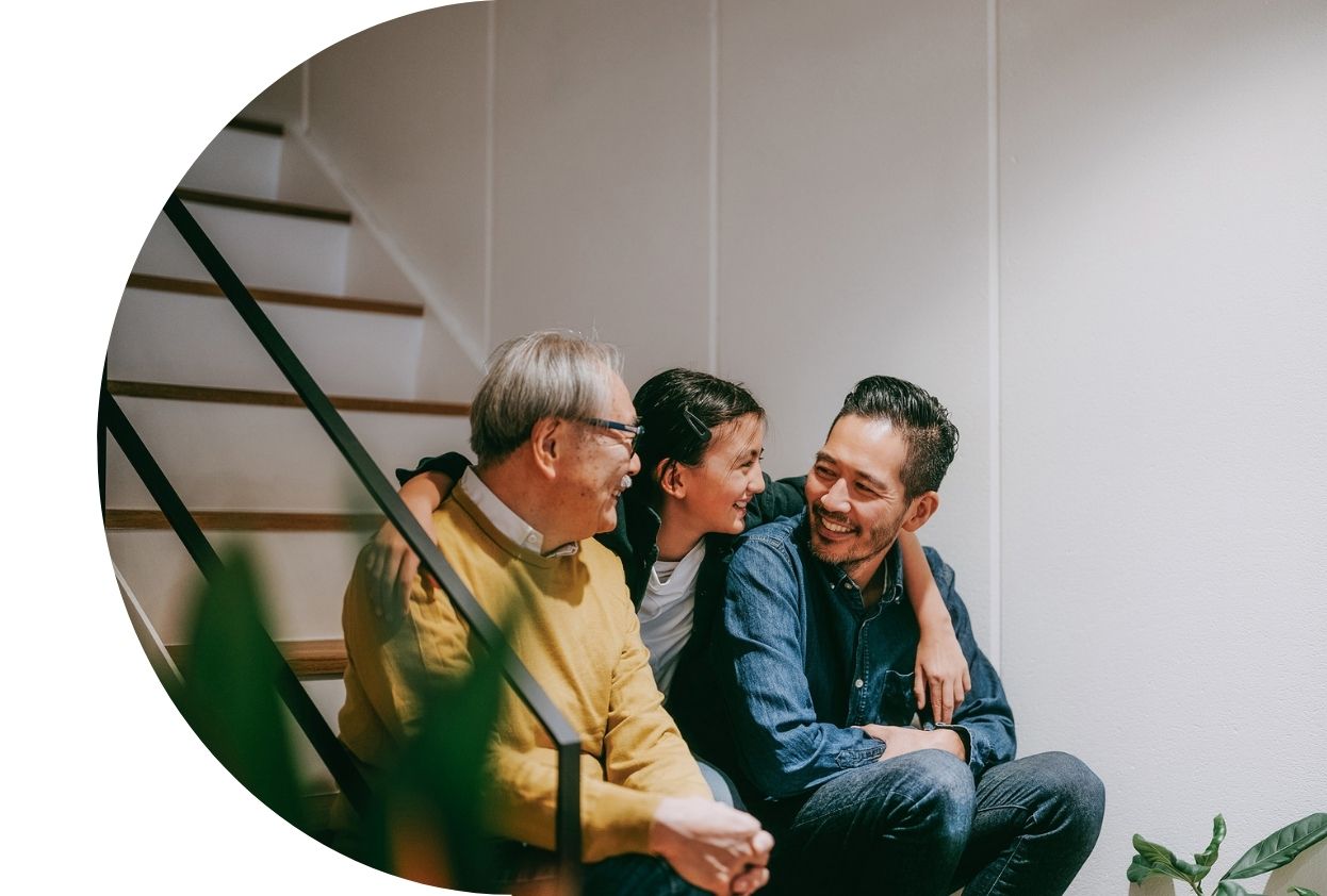 Multigenerational family sitting on an indoor staircase, smiling and laughing together.