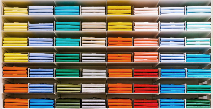 Rows of folded shirts in multiple colours arranged on shelves, representing diversification across a range of investments.