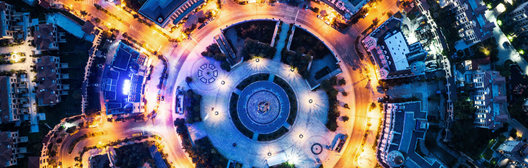 Brightly lit city roundabout surrounded by buildings at night