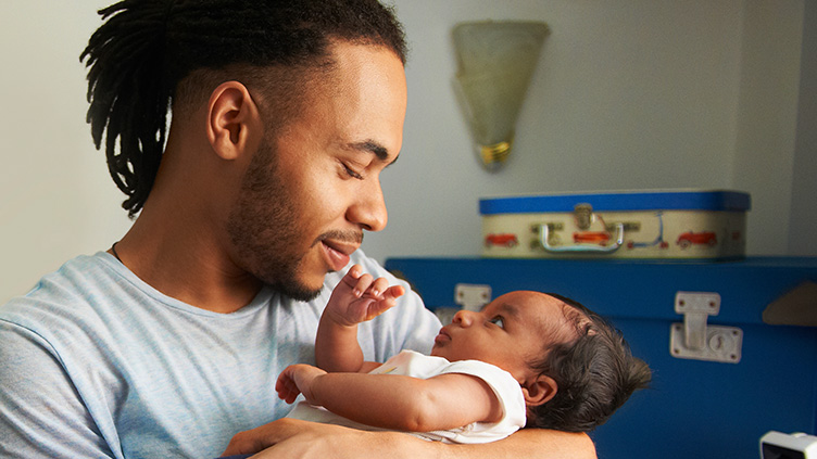 A man holds a newborn baby in his arms