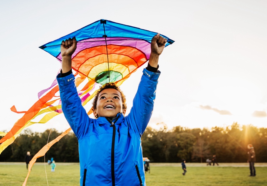 A young boy out in a park enjoying learning how to fly a kite.