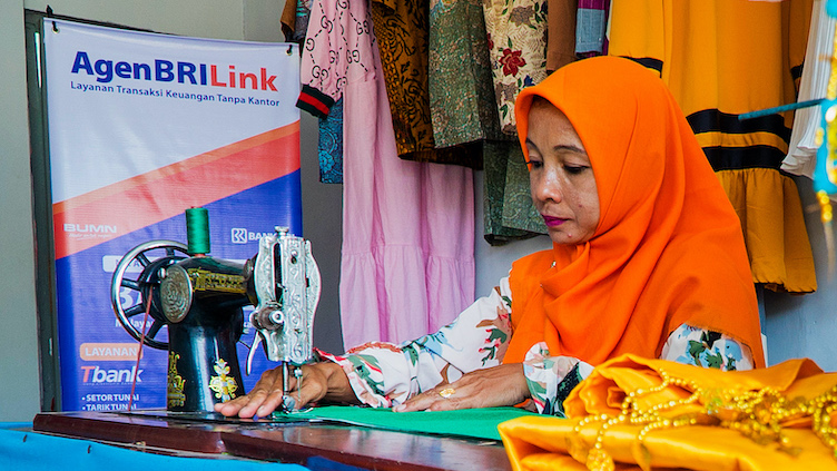 A woman in a clothing shop uses a sewing machine.