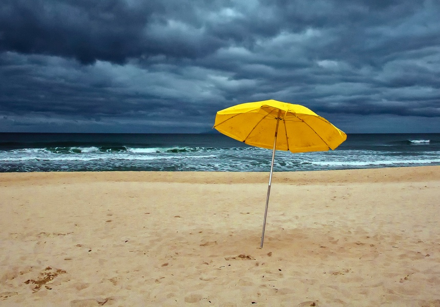 An umbrella in the sand on the beach with an ominous sky