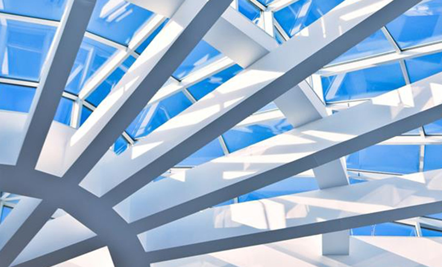 Modern architectural ceiling with intersecting white beams and large glass panels with a bright blue sky above.