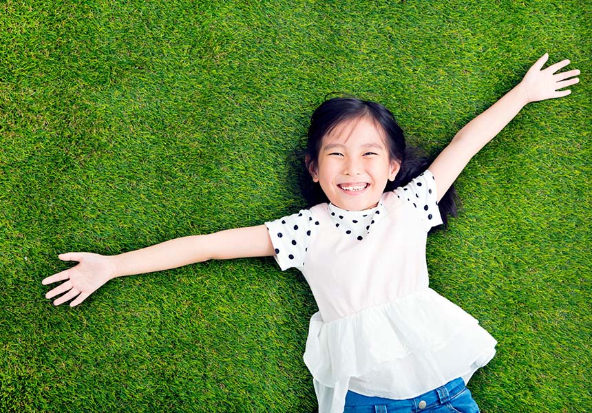 Little girl laying in the grass smiling