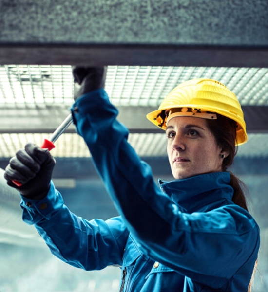 Worker in hard hat using a wrench on industrial equipment