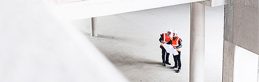 Construction workers evaluate a blueprint.