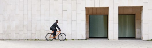 Man riding a bike in front of a builidng