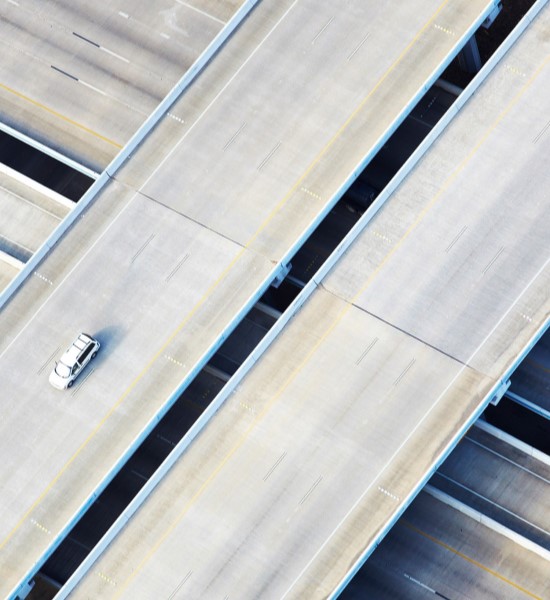 Aerial view of a white car driving on a multi-lane highway
