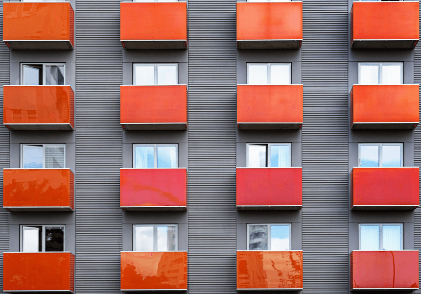 Image shows a front view of a block of apartments with private balconies