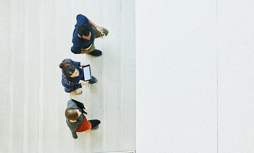 An image of 3 people walking side by side up stairs towards a building