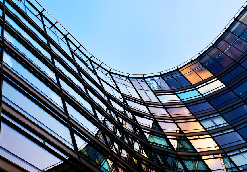 Architectural image of a modern steel and glass structure pointing upward toward a blue sky, symbolizing innovation and forward-looking perspective.