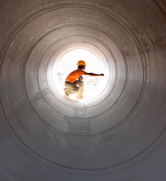 An image of a man with an orange hat standing in a long pipe