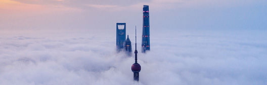 A tall building rises above a sky filled with fluffy clouds, creating a striking contrast against the soft white backdrop.