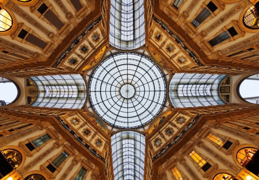 Ornate glass dome ceiling with symmetrical arches and detailed interior architecture.