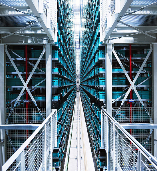 Long corridor inside a data center with rows of server racks and metal support structures.