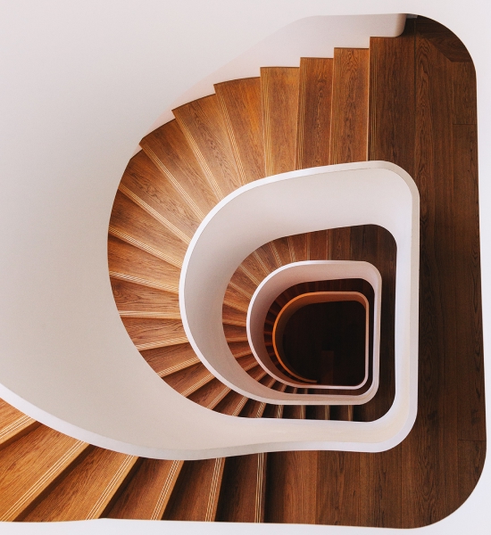 Top‑down view of a spiral staircase with wooden steps and white curved railings