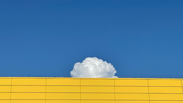 A white cloud above a yellow wall against a blue sky