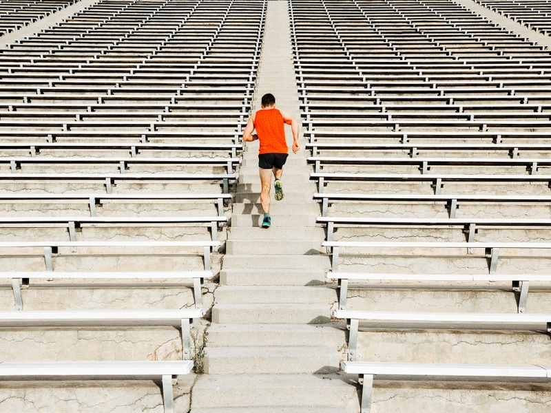 Person running up stadium steps surrounded by rows of empty seating.
