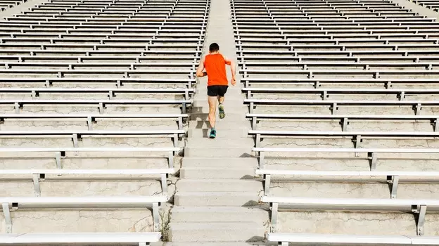 Person running up stadium steps surrounded by rows of empty seating.