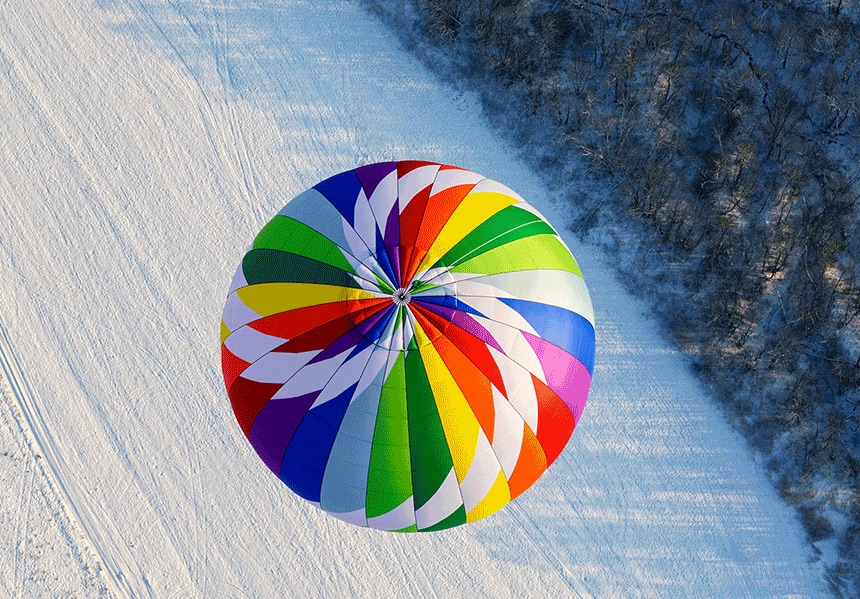Hot air balloon above snow-covered hills