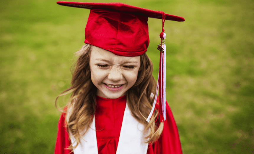 young girl in red graduation cap and gown smiling