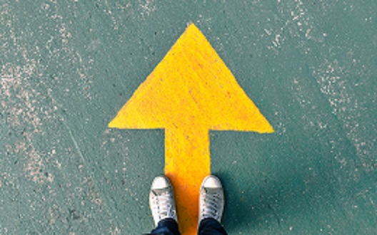 Yellow arrow pointing upwards with feet standing on it at the bottom