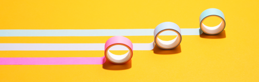 Three thin rolls of tape rolled out parallel to one another over a bright yellow background