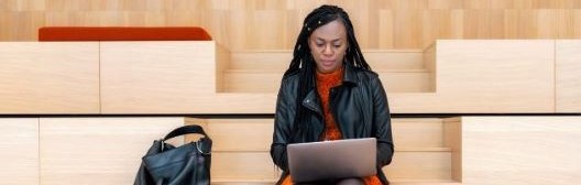 Person sitting on a bench working on a laptop