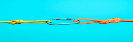  Image shows a carabiner connecting a yellow and orange rope against a blue background